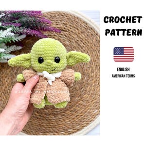 Könnte beinhalten: Gehäkelte grüne und braune Amigurumi-Puppe mit großen Ohren, schwarzen Augen und einem weißen Kragen. Die Puppe trägt einen braunen Mantel. Der Text "CROCHET PATTERN" und "ENGLISH AMERICAN TERMS" ist ebenfalls sichtbar.