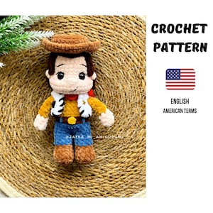 Könnte beinhalten: Gehäkelte Cowboy-Puppe mit braunem Hut, gelbem Hemd, blauer Jeans und braunen Stiefeln. Die Puppe hat eine weiße Weste mit schwarzen Details und ein rotes Halstuch. Der Text "CROCHET PATTERN" und "ENGLISH AMERICAN TERMS" ist sichtbar.