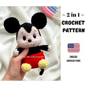 Peut inclure: Une poupée Mickey Mouse au crochet avec des oreilles noires, des bras noirs et un bas rouge. La poupée a des pieds jaunes et un visage souriant. L'image comprend le texte "2 en 1 Crochet Pattern" et "English American Terms".
