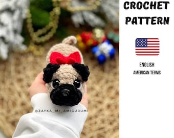 May include: A crocheted pug dog with a red bow. The pug has black ears and a black snout. The image includes the text "CROCHET PATTERN" and the American flag, with the words "ENGLISH AMERICAN TERMS".