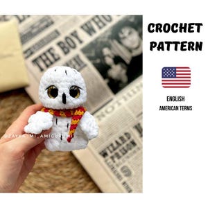 Könnte beinhalten: Eine weiße Häkel-Eule mit einem rot-goldenen Schal, schwarzen Augen und goldenen Akzenten. Das Bild enthält den Text "CROCHET PATTERN" und "ENGLISH AMERICAN TERMS".