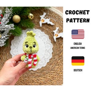 Puede incluir: Un personaje verde tejido a ganchillo con una bufanda a rayas rojas y blancas. El personaje tiene una cara sonriente y sostiene un objeto pequeño. La imagen también incluye el texto "CROCHET PATTERN" y "ENGLISH AMERICAN TERMS".