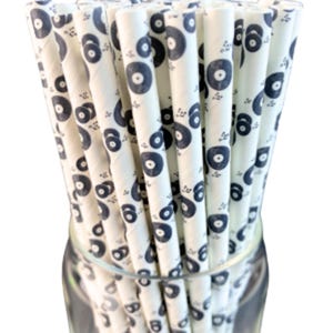 Op de afbeelding: Een bundel witte papieren rietjes met een zwart-wit vinylplaatpatroon. De rietjes zijn gebundeld en staan rechtop in een glazen pot.