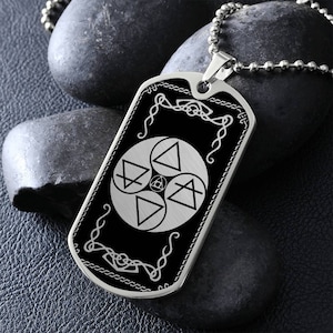 May include: A silver-toned dog tag pendant on a ball chain. The pendant features a black rectangular face with a central circular design containing four triangular elemental symbols and a small central emblem, framed by white decorative line work.