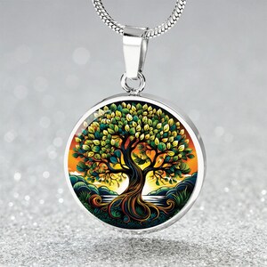 May include: A silver-toned pendant necklace featuring a round pendant with a colorful tree of life design. The tree has green leaves, a brown trunk, and a vibrant sunset background. The necklace chain is a thin, silver-colored snake chain.