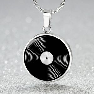 May include: A silver necklace with a round pendant featuring a black and white vinyl record design.