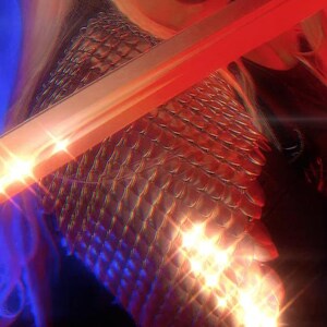 Peut inclure: Gros plan sur un haut en cotte de mailles brillant et iridescent avec une lumière rouge et bleue qui s'y reflète.