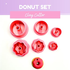 May include: A pink donut set with the text "DONUT SET" and "Clay Cutter". The set includes six pink clay cutters in various sizes and shapes, along with a finished donut. The cutters are round and fluted.