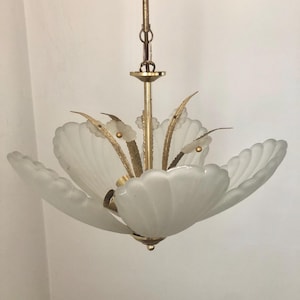 May include: A vintage chandelier with a floral design. The fixture features a gold-toned metal frame with frosted white glass petals. The chandelier is suspended from a gold chain and ceiling mount.