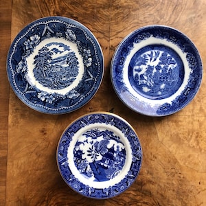 Könnte beinhalten: Drei blaue und weiße Porzellanplatten mit goldfarbenem Rand. Die Teller zeigen ein traditionelles chinesisches Design mit einem blauen und weißen Blumenmuster.