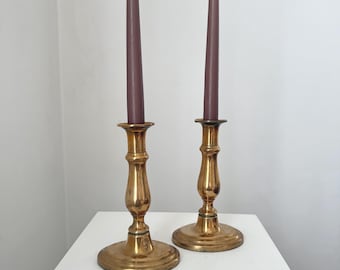 Par de candelabros vintage de latón con base ovalada y portavelas cónicos de oro rosa.