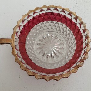 May include: A clear glass bowl with a red and gold rim. The bowl has a diamond pattern and a raised centre.
