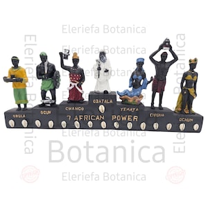 May include: A set of seven small figurines representing the seven African Powers, each with a different color scheme and holding a unique object. The figurines are arranged on a black base with the names of each power written below them. The base is decorated with a row of white cowrie shells.