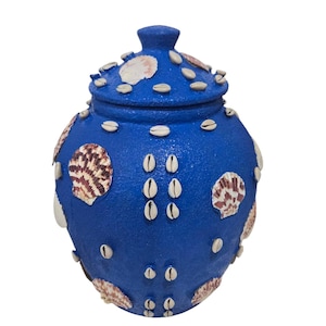 Könnte beinhalten: Eine blaue Keramikdose mit Deckel, verziert mit Muscheln und Kaurischnecken.