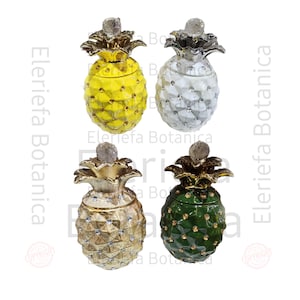 May include: Four ceramic pineapple shaped containers with gold and crystal accents. The pineapples are yellow, white, gold, and green.