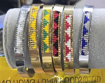Puede incluir: Seis pulseras de cuentas con diferentes patrones de colores. Las pulseras están hechas de metal plateado y dorado. Los patrones incluyen blanco, amarillo, verde, negro, rojo y azul.