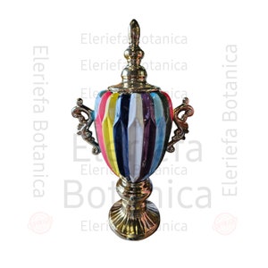 Può includere: Un vaso in ceramica dorata con un designo a strisce colorate. Il vaso ha un corpo rotondo con un manico decorativo su ogni lato. Il vaso ha una base dorata con un designo decorativo.