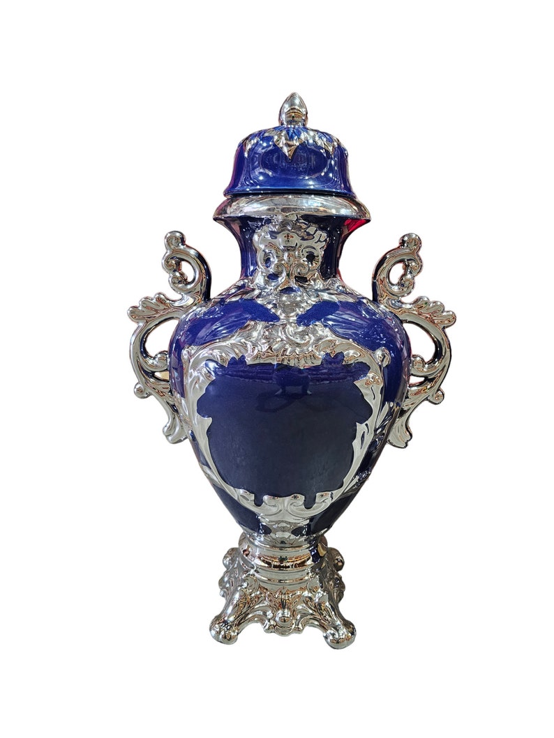 Pode incluir: Um vaso de cer&acirc;mica azul e prata com tampa e detalhes ornamentados. O vaso tem um corpo redondo com uma base larga e duas al&ccedil;as. A tampa &eacute; decorada com um desenho floral.