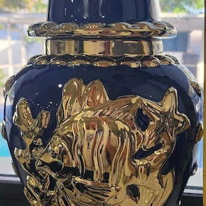 Può includere: Un vaso in ceramica blu e oro con un coperchio. Il vaso è decorato con un disegno di pesce dorato e alghe.