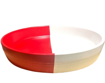 May include: A two-tone oval serving dish. One half is bright red, the other is white. The dish has a smooth, glossy finish and a slightly raised rim. Suitable for serving food, it is likely made of plastic.
