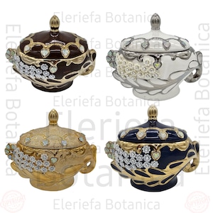 May include: Four ceramic serving bowls with lids. The bowls are decorated with gold trim and white flowers. The lids have heart-shaped accents. The bowls are in four colors: brown, white, gold, and blue.