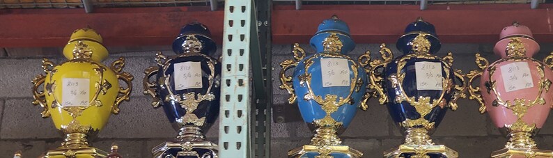 Pode incluir: Cinco bules de ch&aacute; de ouro e cer&acirc;mica adornados com al&ccedil;as decorativas. Os bules s&atilde;o de v&aacute;rias cores, incluindo amarelo, azul e rosa. Cada bule tem um r&oacute;tulo com o texto "2014 5th Annual"