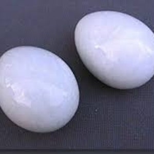 May include: Two white ceramic eggs, each with a slightly different texture and a smooth, glossy finish.