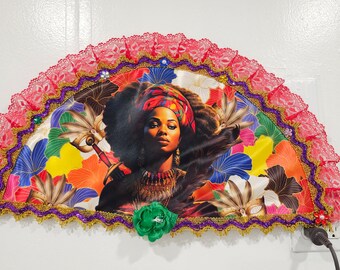 Peut inclure: Un éventail coloré avec un visage de femme au centre. L'éventail est décoré de dentelle, de paillettes et de perles. La femme porte un turban rouge et or et un collier. L'arrière-plan est un motif floral.