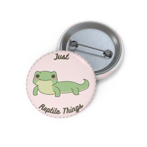 May include: A pink button with a cartoon green lizard and the text "Just Reptile Things".