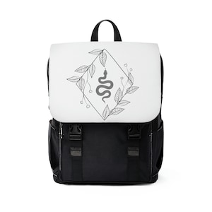 Pode incluir: Mochila preta com um painel frontal branco que apresenta um desenho em preto e branco de uma cobra dentro de um diamante com folhas e flores.