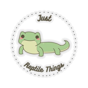 May include: A white circle with a black dashed line border. Inside the circle is a cartoon green lizard with pink cheeks. The text "Just Reptile Things" is written below the lizard in brown text.