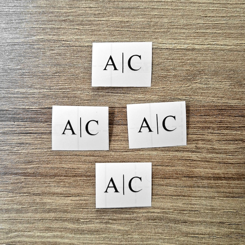May include: Four white square cards with the letters "A|C" printed in black on each card.