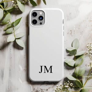 May include: White phone case with a black monogram of the initials "JM".