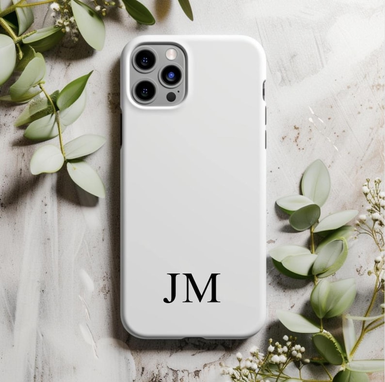 May include: White phone case with a black monogram of the initials "JM".