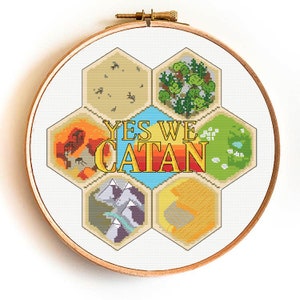 May include: Cross-stitch embroidery in a wooden hoop. The design features a colorful, hexagonal board game layout with the text "YES WE CATAN" in the center. The game board includes various terrain types.