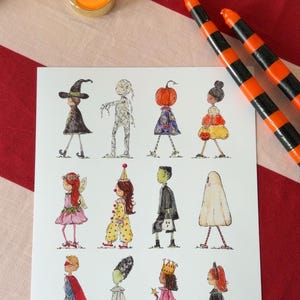 Op de afbeelding: Een witte rechthoekige kunstdruk met twaalf aquarelillustraties van figuren in Halloween-kostuums, waaronder een heks, mummie, pompoenfiguur, clown, geest, superheld en prinses, gerangschikt in drie rijen van vier figuren.
