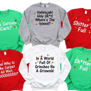 May include: Six Christmas sweaters with different funny sayings. The sweaters are in green, red, white, and gray. The sayings include "You Serious Clark?", "Hallelujah! Holy Sh*t! Where's The lylenol?", "Shitter's Full", "And Why Is The Carpet All Wet, TOOODDDDD?", "In A World Full Of Grinches Be A Griswold", and "Sh*tter's Full".