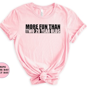 May include: Pink t-shirt with black text that reads "More Fun Than Two 20 Year Olds".