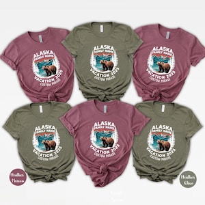 Peut inclure: Six t-shirts &agrave; manches courtes de couleurs marron, vert olive et rose, avec l'inscription "ALASKA FAMILY NAME VACATION 2025 CUSTOM PHRASE" et un motif d'ours. Les t-shirts sont en tissu doux.
