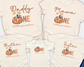 May include: Cream-colored family matching t-shirts and a onesie. Each shirt features a pumpkin graphic and the words "Daddy," "Mama," "Brother," "Sister," or "ONE" with "little pumpkin" below. The shirts are short-sleeved.