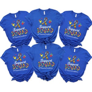 May include: Six royal blue t-shirts with a white graphic of a puzzle piece ribbon with colorful puzzle pieces and the text "Support Squad #TeamCustom".