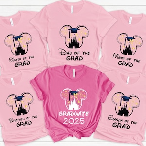 May include: Pink t-shirts with a graduation theme. Each shirt features a Mickey Mouse head design with a graduation cap and castle silhouette. Text on the shirts includes "Sister of the Grad", "Dad of the Grad", "Mom of the Grad", "Brother of the Grad", "Graduate 2025", and "Grandpa of the Grad".