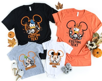 May include: A set of four Halloween-themed t-shirts featuring Mickey Mouse ears with different Disney characters inside. The shirts are in black, orange, gray, and white. The text on the shirts reads "CUSTOM TEXT", "BROTHER", and "BIRTHDAY GIRL".