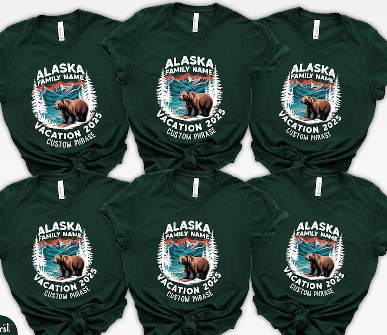 Peut inclure: T-shirts vert fonc&eacute; avec un motif circulaire repr&eacute;sentant un ours brun, des montagnes et le texte "ALASKA FAMILY NAME VACATION 2025 CUSTOM PHRASE". Le motif est en blanc et dans les tons de marron et de bleu.