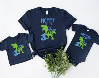 May include: Three navy blue t-shirts with a green dinosaur graphic and the text "Mommy of the Three Rex", "Brother of the Three Rex", and "Three Rex".