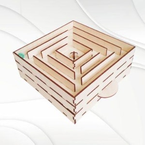 May include: A wooden maze with a square base and multiple levels. A small green marble is visible in the maze.