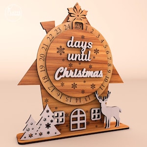 May include: Wooden Christmas countdown calendar in the shape of a house. The clock face reads "days until Christmas" with numbers around the edge. Includes a deer, Christmas trees, and snowflake cutouts. The calendar is made of wood.