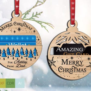 May include: Wooden Christmas ornament with a slot for a gift card. One ornament has the text "MERRY CHRISTMAS" and "AMAZING GIFT CARD". The other ornament has the text "MERRY CHRISTMAS", "For: Ashley... From: Dad..." and a forest design.
