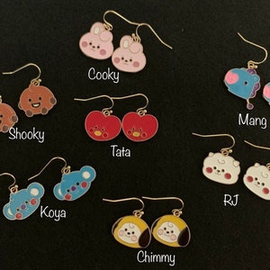 May include: A set of 10 pairs of dangle earrings featuring characters from the BT21 line. The earrings are gold-toned and feature characters like Cooky, Shooky, Tata, Mang, Koya, RJ, and Chimmy.