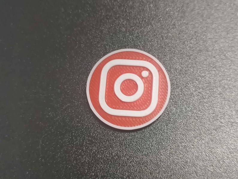 Pu&ograve; includere: Logo Instagram rotondo, rosso e bianco. Il logo presenta un contorno bianco e un'icona della fotocamera bianca al centro. Lo sfondo &egrave; di colore grigio scuro.